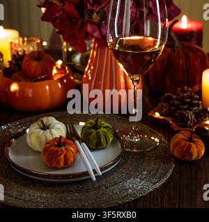 Ein wunderschön gedeckter Tisch für eine Herbstfeier zeigt kleine Samtkürbisse in verschiedenen Farben, darunter Orange, Grün und Weiß, p Stockfoto