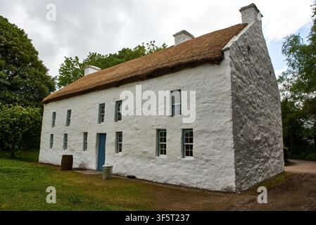 Historisches zweistöckiges strohgedecktes Steingebäude mit blauer Tür und Fenstern im Ulster American Folk Park nahe Omagh, County Tyrone, Nordirland. Stockfoto