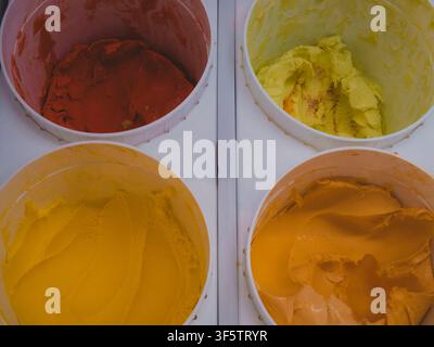 Ansicht von oben auf vier farbenfrohe Becher handwerklich hergestellter Eiscreme oder Gelato in den Geschmacksrichtungen Rot, Gelb und Orange Stockfoto