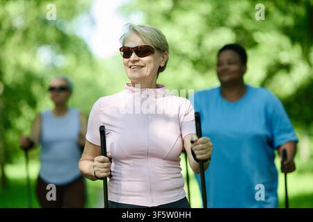 Seniorin Nordic Walking mit verschiedenen Freunden im Park Stockfoto