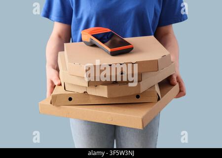Lieferdienstmitarbeiter hält einen Stapel Pizzakartons mit einem Zahlungsterminal oben drauf, Lebensmittellieferdienst Stockfoto