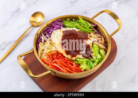 Koreanischer Bibimbap-Reis mit gebratenem Ei, Gemüse und Gochujang-Sauce in einer goldenen Schüssel Stockfoto