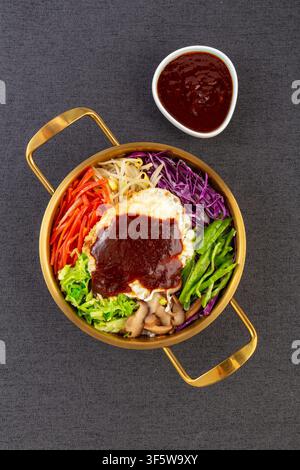 Koreanischer Bibimbap-Reis mit gebratenem Ei, Gemüse und Gochujang-Sauce in einer goldenen Schüssel Stockfoto