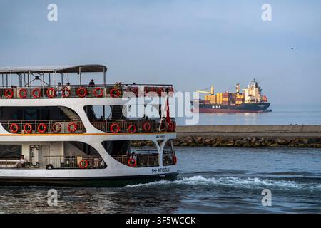 Istanbul, Türkei. 4. Aug., 2026. Eine Passagierfähre bewegt sich durch ruhiges Wasser in der Nähe eines Wellenbrechers, während ein Frachtschiff im Hintergrund in Istanbul, Türkei, navigiert. (Credit Image: © Moe Zoyari/ZUMA Press Wire) NUR FÜR REDAKTIONELLE VERWENDUNG! Nicht für KOMMERZIELLE VERWENDUNG! Stockfoto