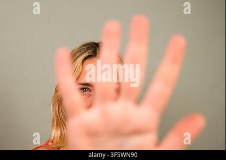 Frau, die ihre Hand ausstreckt und mit ernstem Gesichtsausdruck ein Stopp oder eine Ablehnung signalisiert Stockfoto