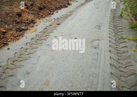 Schwere Reifenspuren auf sandigem Straßenbett an einer ziviltechnischen Baustelle in der Vorstadt. Konzept: Infrastrukturerneuerung Stockfoto