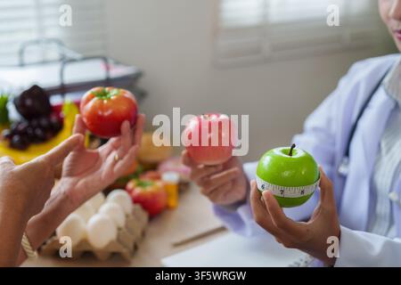 Ernährungsberater hält einen grünen Apfel mit Maßband während der Beratung eines Patienten für einen gesunden Ernährungsplan Stockfoto