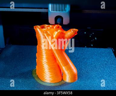 Prozessdruck auf 3D-Drucker. Der 3D-Druckprozess aus geschmolzenem orangefarbenem Kunststoff. 3D-Drucktechnologie. FDM-Technologien. Fused Deposition Modeling. Additives Fertigungsverfahren. Stockfoto