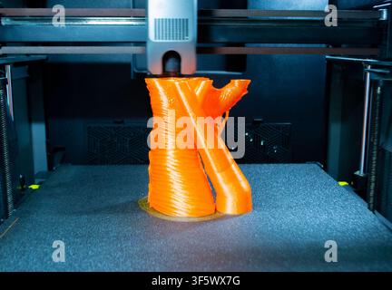 Prozessdruck auf 3D-Drucker. Der 3D-Druckprozess aus geschmolzenem orangefarbenem Kunststoff. 3D-Drucktechnologie. FDM-Technologien. Fused Deposition Modeling. Additives Fertigungsverfahren. Stockfoto