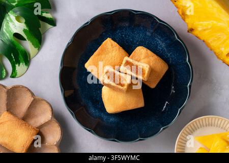 Traditionelles taiwanesisches Ananaskuchengebäck mit reichhaltiger Füllung und Ananas im Hintergrund. Stockfoto