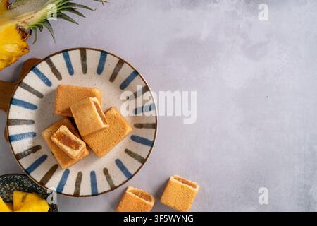 Traditionelles taiwanesisches Ananaskuchengebäck mit reichhaltiger Füllung und Ananas im Hintergrund. Stockfoto