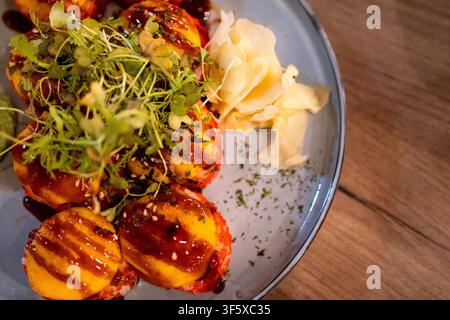 Gebackene Sushi-Rolle mit Garnelen, Käse und karamellisierter Sauce auf dem Teller. Japanisches Sushi-Konzept für Restaurantessen und asiatische Esskultur. Stockfoto