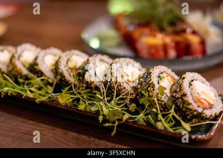 Philadelphia-Sushi-Rolle mit Sesamsamen, serviert neben einer gebackenen Garnelen- und Käserolle. Japanisches Sushi-Konzept für Restaurantessen und asiatische Küche Stockfoto