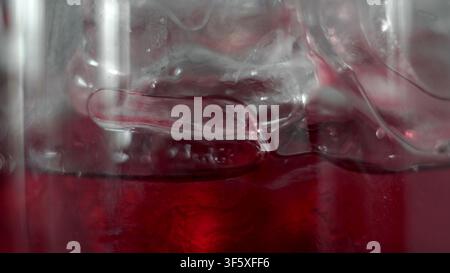 Rotes Getränk, das in einem Glas mit groben Eiswürfeln kühl ist und ein erfrischendes, kühlendes Gefühl vermittelt Stockfoto