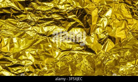 Gold zerknitterte Aluminiumfolien-Textur-Hintergrund hoch kontrastiert Stockfoto