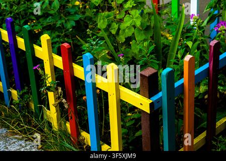 Mehrfarbiger Regenbogen-Holzzaun im Gartenhintergrund Stockfoto