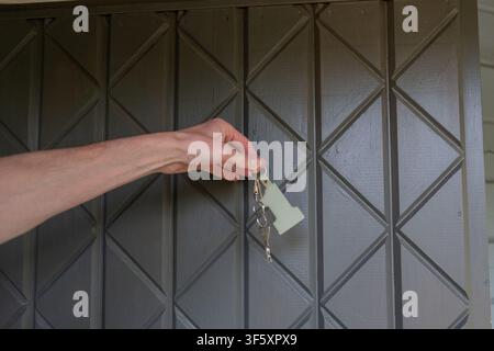 Hand, die Hausschlüssel vor einem Briefkasten für Wohnimmobilien hält, nach Zugang zur Immobilie oder nach der Überprüfung der Wohnungsmiete Stockfoto