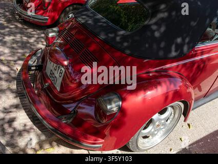 Tavernes Blanques, Spanien - 14. Juni 2026. Ein klassischer Volkswagen Beetle in metallischem Rot steht in einer Reihe mit anderen Autos. Die Ansicht zeigt den Motor li Stockfoto