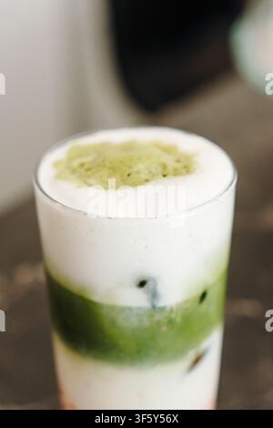 Frisch zubereiteter Erdbeer-Matcha-Latte mit cremigem Schaum und bunten Schichten, serviert über Eis. Modernes Spezialitäten-Kaffeegetränk im Nahaufnahme. Stockfoto