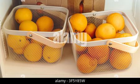 Frische Orangen und Grapefruits in Metallkörben in einem Café gelagert. Helle Zitrusfrüchte schaffen eine gesunde und farbenfrohe Auslage. Stockfoto