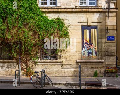 Avignon, Frankreich, 11. April 2026, Fahrrad, das an einem Gebäude mit einem Wandgemälde und einer Kletterpflanze in der Joseph-Vernet-Straße geparkt ist Stockfoto