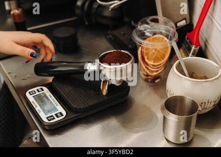Gemahlener Kaffee wird auf einer digitalen Waage abgewogen, bevor er verdichtet und Espresso zubereitet wird. Professioneller Arbeitsablauf in einem Specialty-Café. Stockfoto
