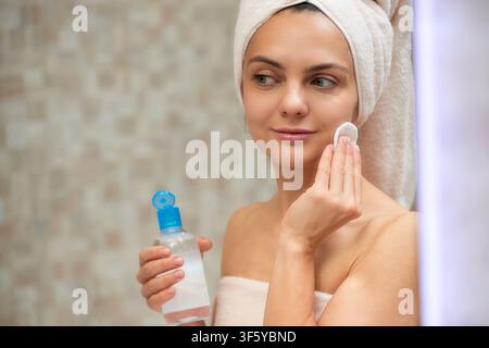 Frau reinigt ihr Gesicht mit einem Wattepad und Toner Stockfoto