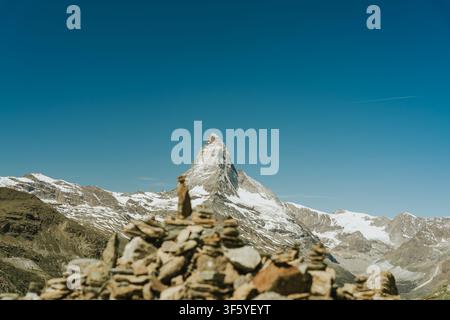 Der Matterhorn-Berg erhebt sich majestätisch mit Schneekappen, gesehen von einem Alpenpfad mit Steinhaufen Stockfoto