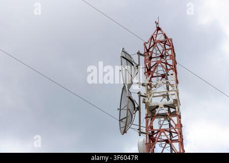Telekommunikationsmast mit roten und weißen Abschnitten, ausgestattet mit mehreren Antennen und Satellitenschüsseln, die Signale auf dem Berg Pantokrator senden Stockfoto