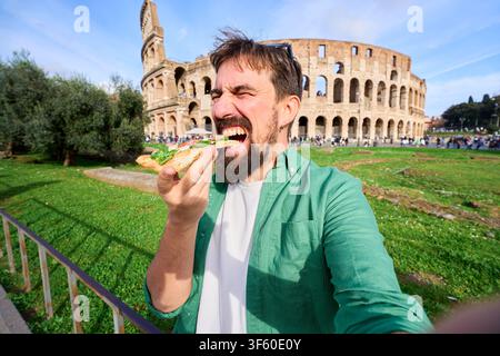 Ein Mann isst ein Stück Pizza mit dem Kolosseum im Hintergrund in Rom. Stockfoto