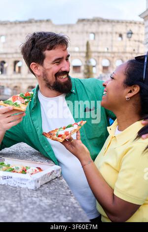 Glückliches Paar, das Pizza vor dem kolosseum in Rom isst. Stockfoto
