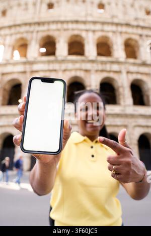 Weiblicher Tourist zeigt Smartphone mit leerem Bildschirm vor dem Kolosseum in Rom. Stockfoto