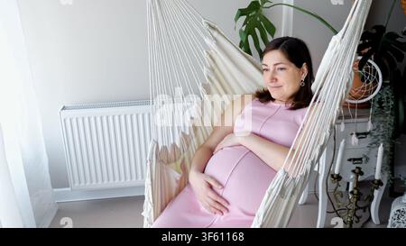 Schwangere Frau entspannt sich in einem hängenden Hammock-Stuhl zu Hause Stockfoto