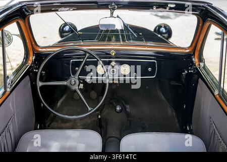 Innensicht eines vintage klassischen schwarzen Autos mit Lenkrad, Armaturenbrett und Vordersitzen. Klassisches Automobil. Stockfoto