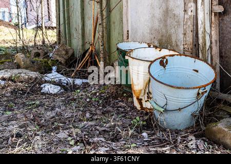 Alte rostige Eimer an einer Scheunenwand auf dem Land. Landleben und Grunge. Stockfoto