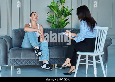 Junge Frau hat eine Beratung mit einer weiblichen Therapeutin auf dem Sofa Stockfoto