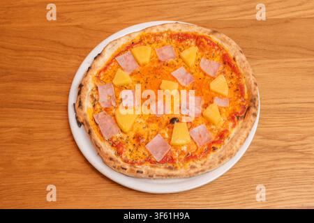 Rustikale Schinkenspizza mit geschmolzenem Mozzarella, Tomatensoße und frischem Basilikum auf Metalltablett Stockfoto