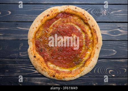 Eine runde glutenfreie Pizza ruht auf einem dunklen Holztisch. Stockfoto