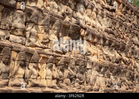 SIEM REAP, KAMBODSCHA - Alte Sandsteinarchitekturdetails, die eine Nahaufnahme, eine schräge Ansicht von sich wiederholenden Reihen kunstvoll geschnitzter Figuren zeigen Stockfoto