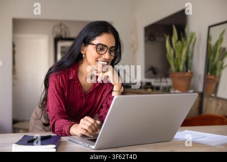 Hübsche indische Studentin studiert online mit Laptop zu Hause Stockfoto