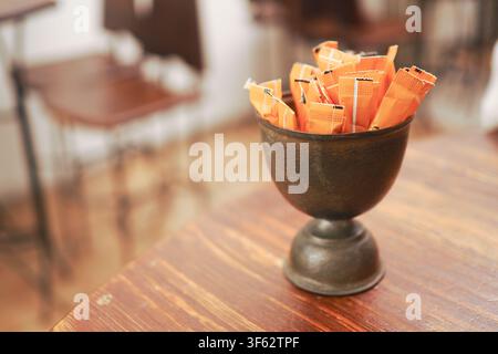Zuckerpäckchen in einer Tasse auf einem Holztisch in einem Café Stockfoto