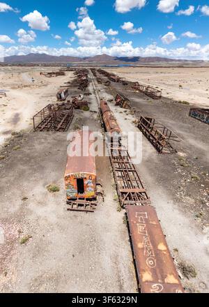 Luftbild des historischen Zugfriedhofs in der Uyuni-Wüste mit verrosteten Dampflokomotiven und verlassenen Zugwagen, die über das Gebiet verstreut sind Stockfoto