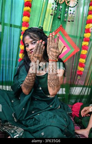 Indische Bengali-Inderin zeigt kunstvolle Henna-Mehndi-Muster auf beiden Händen während der Vorhochzeitszeremonie, trägt ein grünes Saree mit Blumendekor, Stockfoto