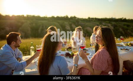 Freunde genießen ein lebhaftes Gespräch während einer Mahlzeit in der goldenen Stunde auf dem Land Stockfoto
