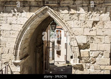 Ein alter Steinbogen rahmt eine schmale Straße und Gebäude, Petralia Sottana, Sizilien, Italien Stockfoto