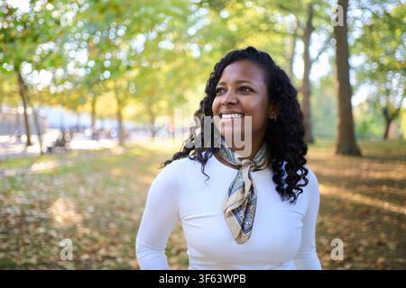Lächelnde schwarze lateinamerikanische Frau genießt den Herbstpark Stockfoto