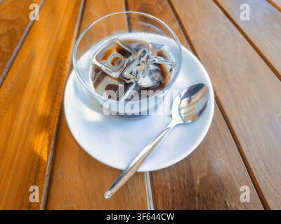 Traditioneller Caffè Leccese (Salento-Eiskaffee), zubereitet mit Espresso, Mandelmilch und Eis, serviert in einem Glas auf einem Holztisch. Eine erfrischende Sommerkaffeespezialität aus Lecce, Salento, Apulien, Italien Stockfoto