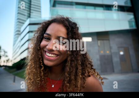 Trendige junge Frau lächelt draußen auf der Straße der Stadt und strahlt Jugendliche Energie aus Stockfoto