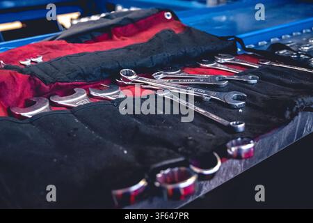 Satz von Metall-Kombinationsschlüsseln, organisiert in einer schwarzen Werkzeugtasche für Mechaniker in der Werkstatt Stockfoto