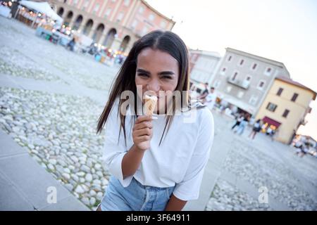 Schwarze lateinamerikanische Touristin isst Eis auf einem europäischen Stadtplatz Stockfoto